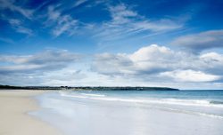 涨潮蓝天白云下的沙滩海岸高清图片