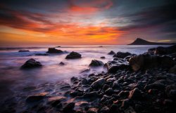 夕阳下的海滩夕阳下的乱石海滩海报背景高清图片