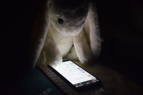 在玩手机的兔子玩偶摄影图片